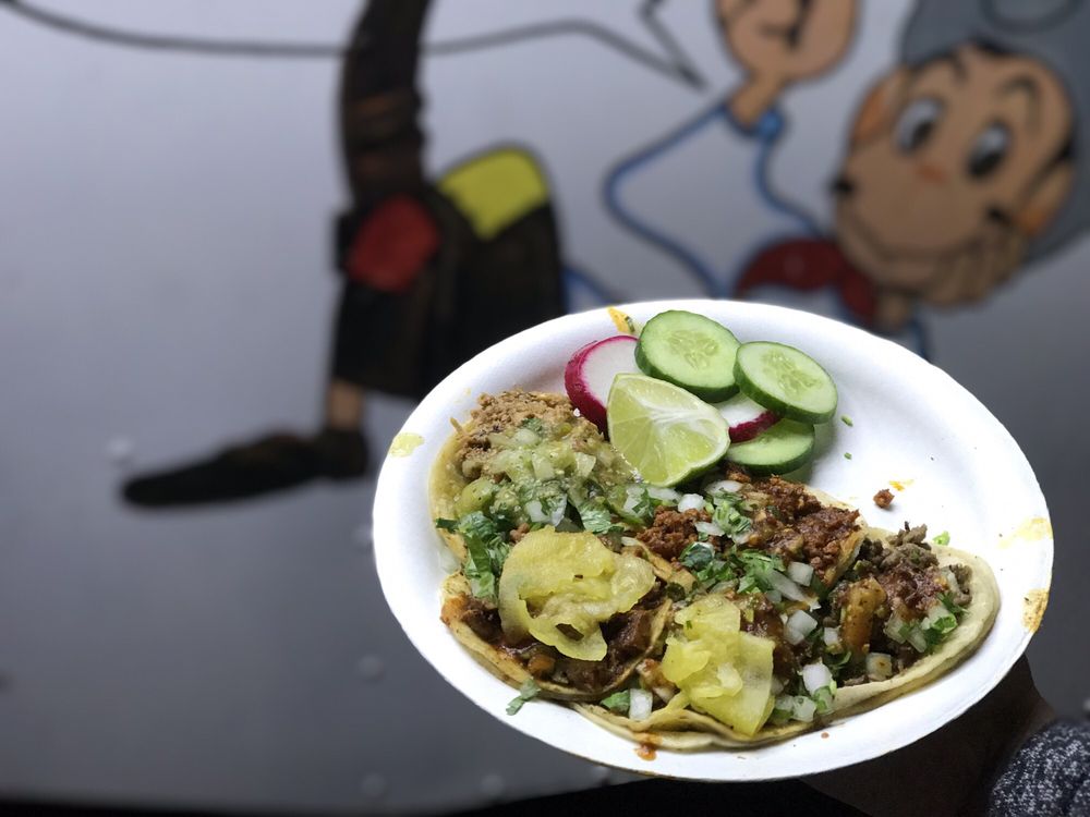 A plate of tacos in front of the truck mural
